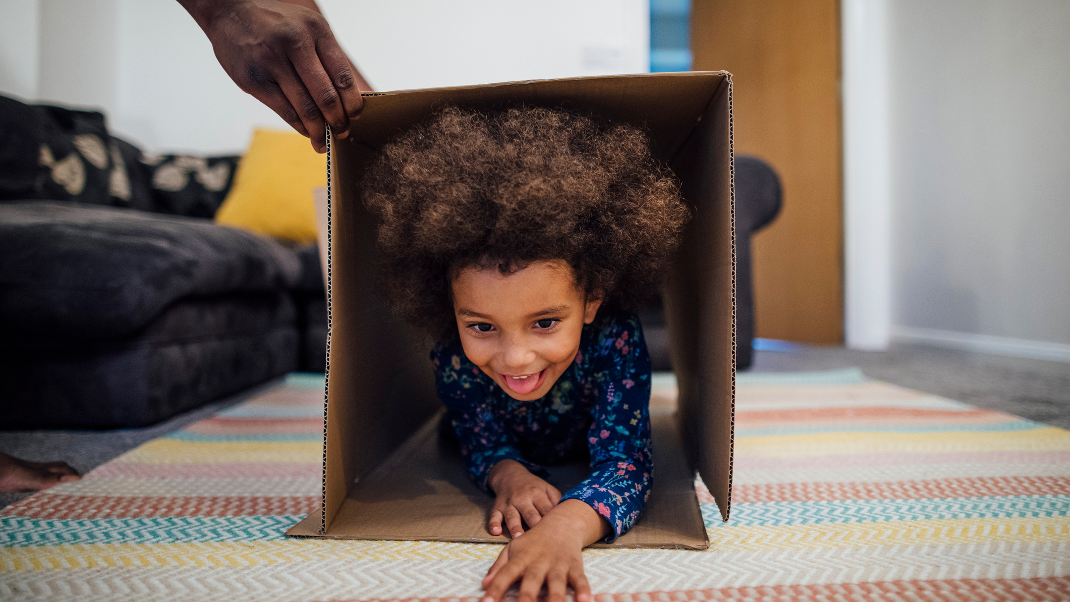 Child crawls through cardboard box