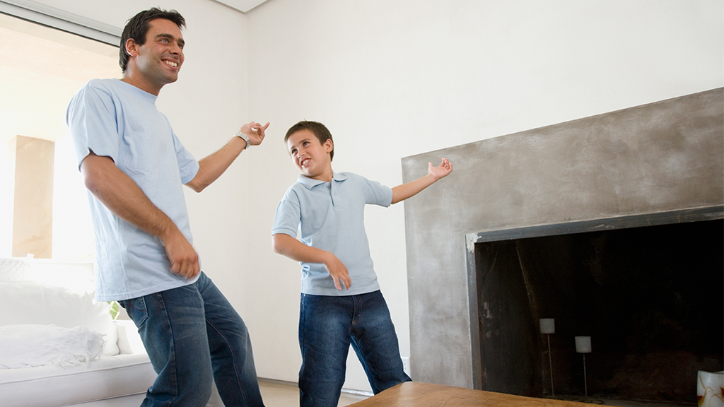 Father and son play air guitar in the living room