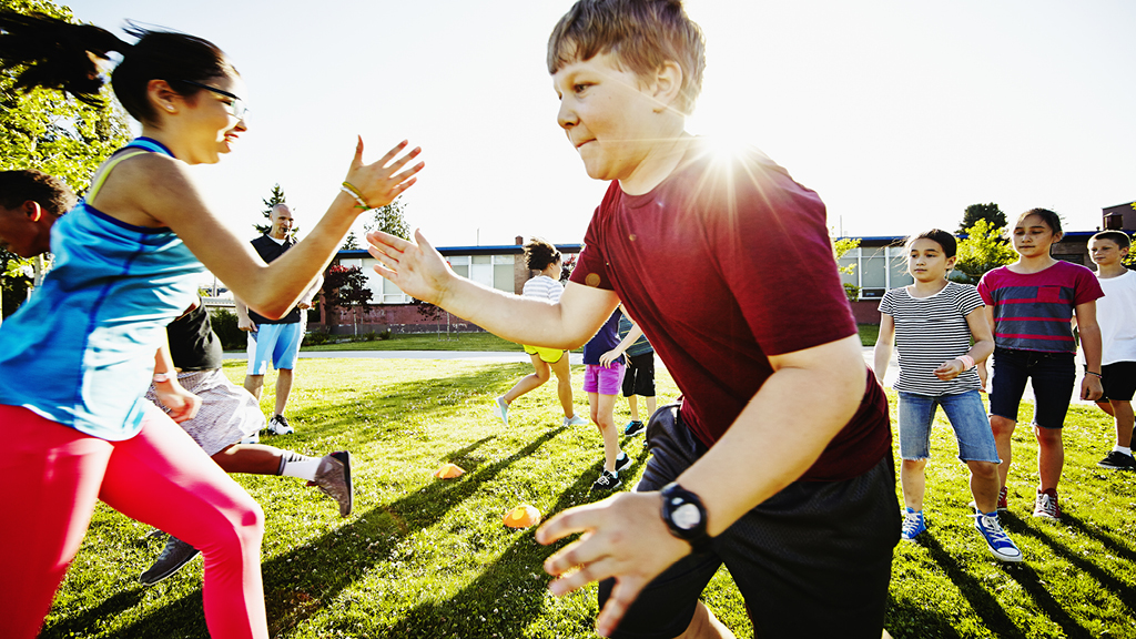 Kids running a relay outside on a grassy field
