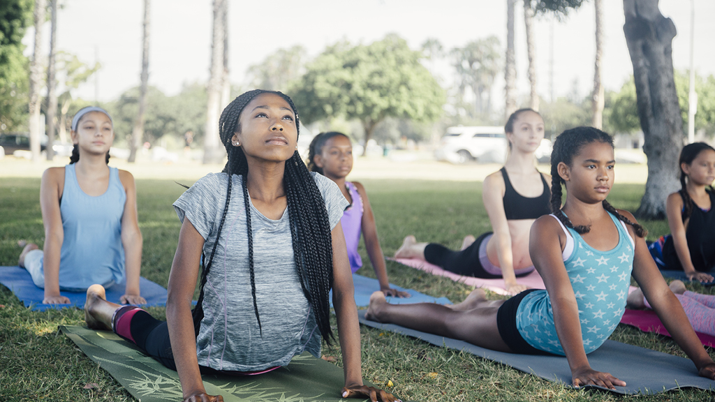 Group of kids doing yoga on mats outside