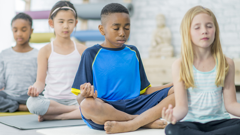 Group of kids doing mindful breathing while sitting with legs crossed