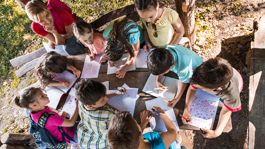 Group of kids sitting together writing on paper