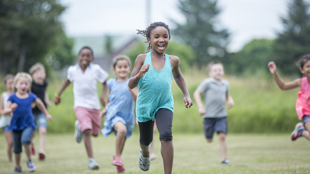 Group of kids running outside on a grassy field