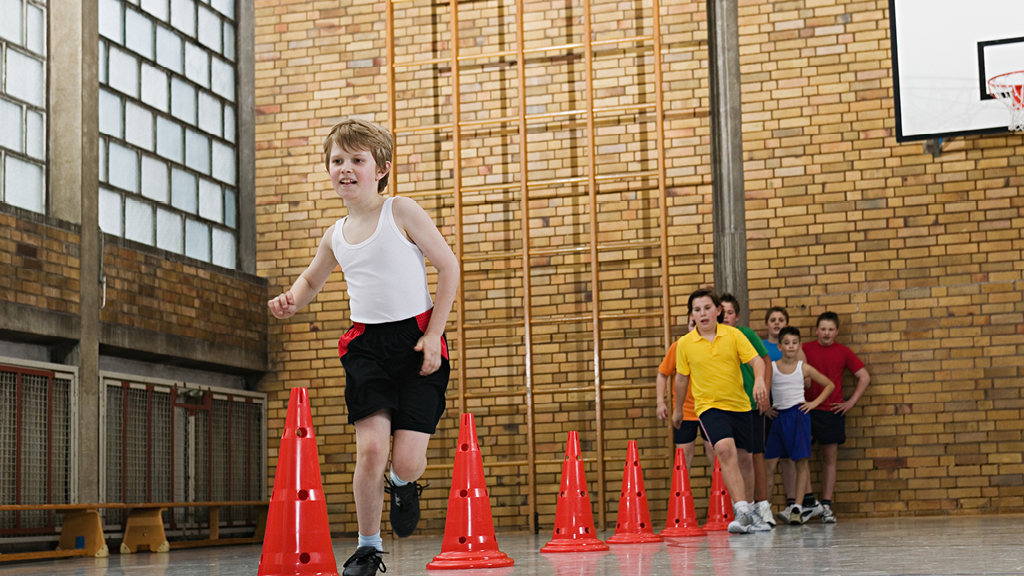 kids running around cones in a gym