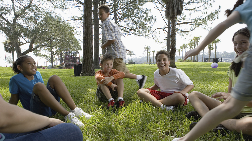 kids sitting on the grass and playing a game